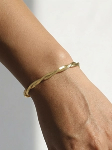 Detail of twisted 18K gold plated herringbone snake chain bracelet on a female wrist