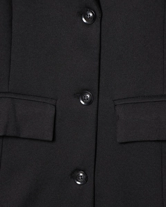 Detail of high-quality twill fabric, sleek black button and pocket on the blazer
