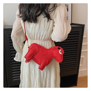 Detail of red horse-shaped animal crossbody bag with gold chain strap on model