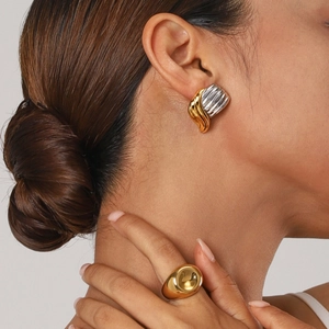 Two-tone wavy stainless steel earrings and polished gold ring set on a female model