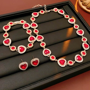 Dettaglio di un set di gioielli vintage con pietre rosse a cuore e piccoli diamanti