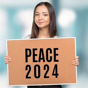Detail of a woman holding a cork board with black PEACE 2024 vinyl letter stickers