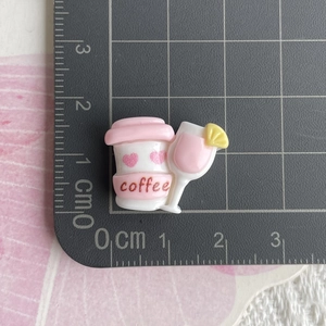 Dettaglio di ciondoli in resina caffè e cocktail con cuore rosa su griglia graduata
