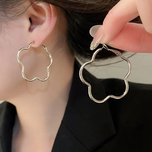 Detailed view of silver wavy flower hoop earrings with polished metallic mirror finish