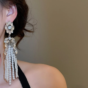 Detail of luxury long tassel drop earrings with crystals and white pearls on female model