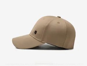 Close-up of khaki baseball cap side profile with small black shield emblem and fine stitching