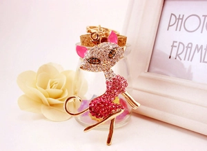 Macro shot of gold cat keychain with pink and white crystals next to a white frame