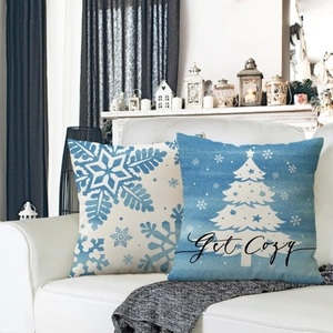 Blue snowflake and Christmas tree linen pillow covers displayed on a white sofa