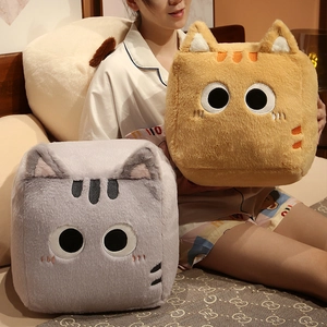 Close-up of soft plush cat pillows in grey and orange shown in a cozy bedroom setting