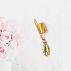 Close-up of golden metal dreadlock ring with a delicate shell pendant accessory