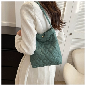 Detail of green tote bag with heart-shaped quilted pattern and metallic gold snap closure