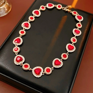 Dettaglio di una collana vintage dorata con cuori rossi e strass su un astuccio nero