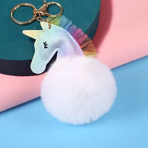 Detalle de llavero de unicornio brillante con pompón de pelo sintético y oro metal