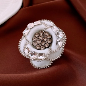 Detail of camellia flower brooch with rhinestones on brown satin background