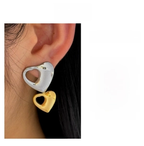 Dettaglio degli orecchini a cuore bicolore indossati con design a strati oro e argento