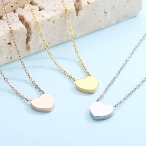 Three minimalist heart pendant necklaces in rose gold, gold, and silver finishes