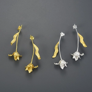 Detailed view of tulip drop earrings in gold and silver finish with brushed metal texture