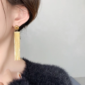 Detail view of long gold tassel earrings on model showcasing elegant drape and length
