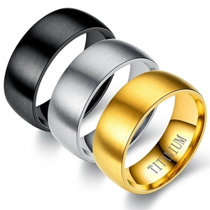 Close-up of brushed titanium steel rings in black, silver, and gold with engraved detail