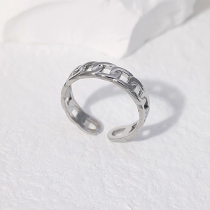 Detailed close-up of a silver chain-style open ring on a clean white textured surface
