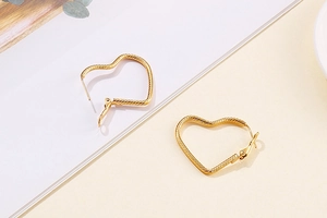 Detailed close-up of gold heart hoop earrings with elegant textured spiral finish