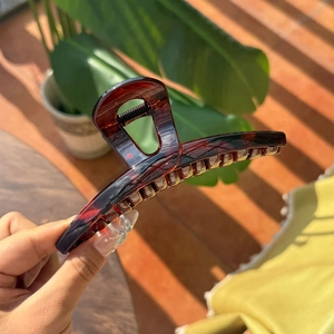 Close-up of red-brown tortoiseshell hair claw with strong alloy spring in natural sunlight