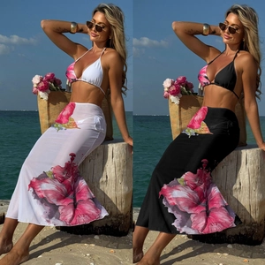 Detail of floral bikini set and mesh maxi skirt with hibiscus print on beach background