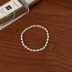 Exquisite gold-plated tennis bracelet with marquise-cut zircons on a wooden table