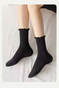 Detailansicht schwarzer gerippter Crew-Socken mit eleganten Rüschenrändern auf Stoff