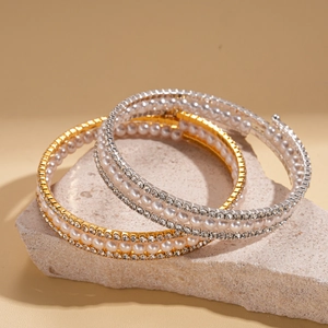 Luxury multilayer spiral bracelet with pearls and rhinestones on stone background