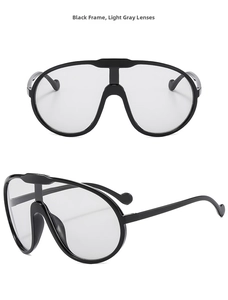 Detail view of large oversized sunglasses with thick black frames and light gray lenses