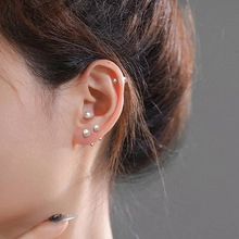 Detail showing various sizes of minimalist silver ball studs worn on model's ear