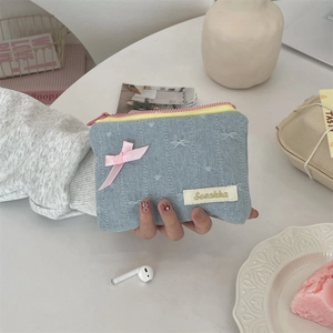 Dettaglio del portamonete in denim con fiocco di raso rosa e ricamo Sozokka