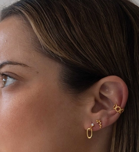 Close-up of gold star earrings and ear cuff with white zircon stones on model