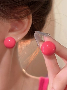 Macro detail shot showing the glossy finish of vibrant pink round stud earrings