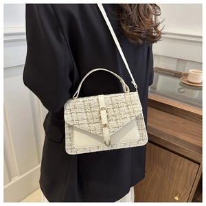 Detail of tweed weave texture and gold buckle on a stylish white crossbody bag