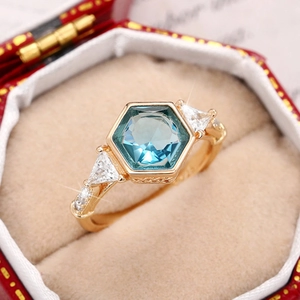 Minimalist gold geometric ring with hexagonal blue gemstone in a red velvet jewelry box
