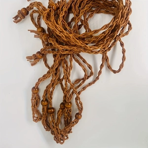 Detail of hand-woven brown cord with polished wooden beads and bohemian tassels