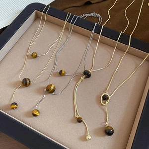 Macro shot of tiger eye stone necklaces with gold and silver chains on a jewelry tray