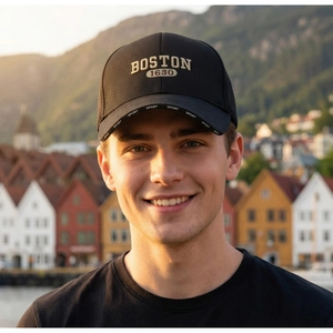 Close-up of black baseball cap with gold Boston embroidery and Sport logo on the brim
