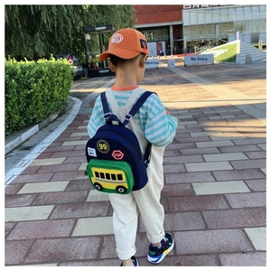Rear view of kid wearing a blue cartoon school bus backpack with STOP sign and EXIT details