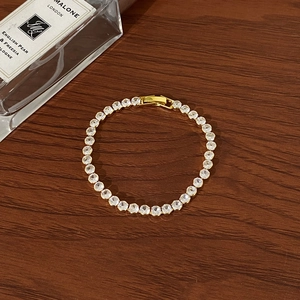Macro shot of gold tennis bracelet with brilliant round zircons on a wooden background