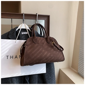 Detail of dark coffee suede tote bag with gold hardware and protective base studs