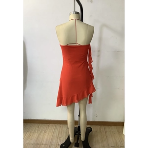 Detail of red backless mini dress featuring asymmetric ruffled hemline on a mannequin