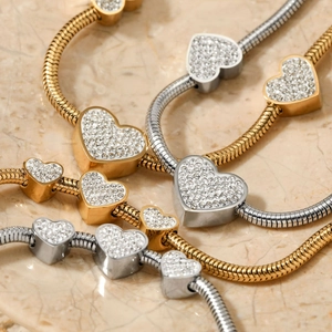 Luxurious gold and silver snake bone bracelets with rhinestone heart charms on marble