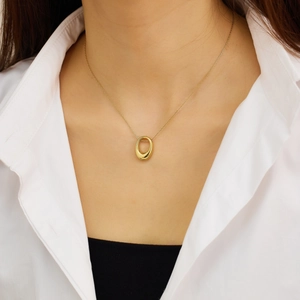 Gros plan d'un collier pendentif ovale doré sur un mannequin en chemise blanche