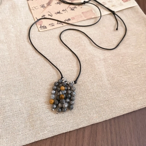 Close-up of ethnic beaded necklace with grey stone beads on linen fabric