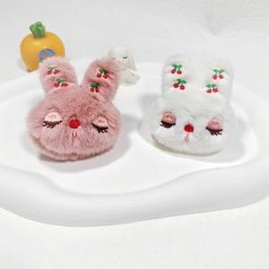 Close-up of pink and white plush bunnies with cherry embroidery and closed eyes