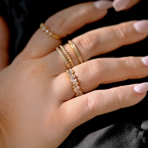 Close-up of golden eternity rings with rectangular zircon stones worn by a model
