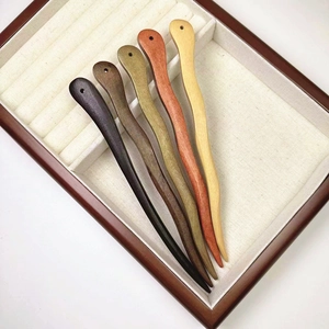 Détail de cinq épingles à cheveux en bois de santal présentées sur un plateau en tissu beige